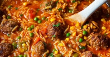 Bunte Orzo-Pfanne mit Hackbällchen auf einem Teller serviert.