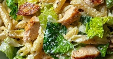 Caesar Nudelsalat mit Römersalat in einer Schüssel, serviert mit Dressing