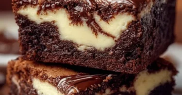 Frischkäse-Brownies auf einem Teller, verziert mit Schokoladensauce.