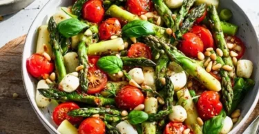 Grüner Spargel Salat mit Tomaten und Mozzarella auf einem Teller