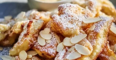 Ein Teller Kaiserschmarrn, fluffig und goldbraun, serviert mit Puderzucker und Früchten.