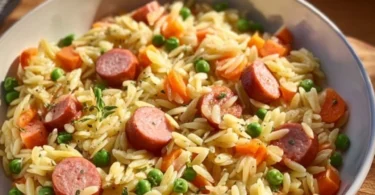 Kritharaki mit Würstchen und frischem Gemüse auf einem Teller angerichtet