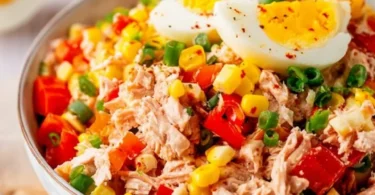 Thunfisch-Salat mit Eiern, Mais und Paprika auf einem Teller angerichtet.